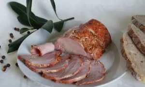 Soczysta kiełbasa z łopatki z szynkowara, pokrojona w plastry, podana z chlebem i liśćmi laurowymi.