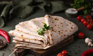 Stos cienkiego, puszystego lawaszu, ozdobiony natką pietruszki, obok pomidorków, papryczki chili i pieprzu. Idealny do wrapów.