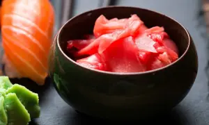 Miseczka z różowym, marynowanym imbirem obok sushi i wasabi. Idealny dodatek do japońskich potraw.