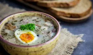 Pyszny żurek z kiełbasą i ziemniakami, ozdobiony jajkiem i natką. Zastanawiasz się, ile kcal ma żurek z kiełbasą i ziemniakami?