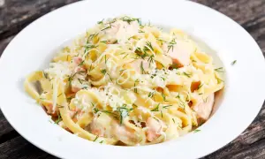 Pyszny makaron z łososiem w kremowym sosie, posypany parmezanem i świeżym koperkiem. Idealny na obiad.