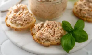 Pyszna pasta rybna na chrupiących grzankach, ozdobiona listkami bazylii. Idealna na szybką przekąskę.