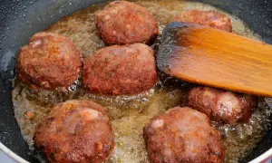 Na patelni smażą się kotlety mielone. Drewniana łopatka pomaga przewracać je, by równomiernie się zarumieniły.