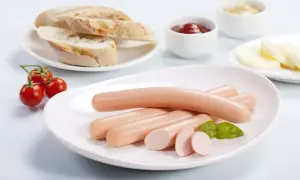 Parówki drobiowe na talerzu z pieczywem i pomidorkami. Czy cukrzyk może jeść parówki drobiowe? Odpowiedź zależy od składu i ilości.