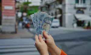 Ręce trzymają pięć banknotów po 1000 forintów. Tyle forintów kosztuje obiad na Węgrzech?