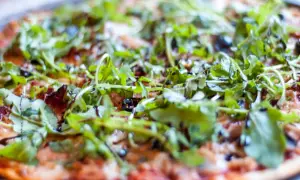 Pyszna pizza z tuńczykiem, rukolą i oliwkami, polana sosem balsamicznym. Idealna na szybki obiad.