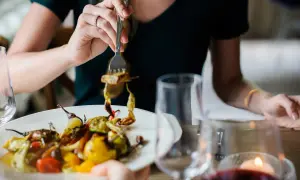 Kobieta je warzywa z grilla, zastanawiając się, ile kcal na obiad.