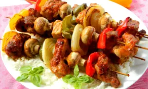 Szaszłyki z karkówki z pieczarkami, papryką i cebulą na ryżu. Aromatyczne mięso i warzywa tworzą pyszne danie.
