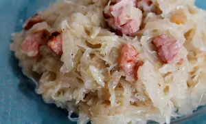 Kapusta kiszona zasmażana z boczkiem, podana na talerzu. Aromatyczne danie, które rozpływa się w ustach.