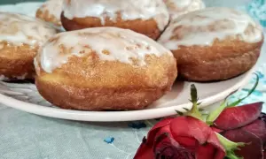 Pączki z ziemniakami Ewy Wachowicz, oblane lukrem, kuszą na talerzu. Obok leży czerwona róża.
