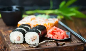 Pyszne sushi z kremowym nadzieniem, obok marynowany imbir i miseczka na sos do sushi.