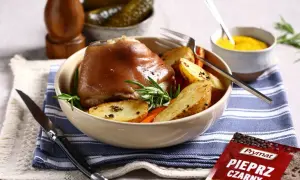 Idealna golonka na obiad, pieczona z ziemniakami i rozmarynem. Obok słoiczek musztardy i ogórki.