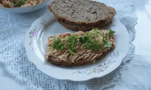 Na talerzu z różanym wzorem leży kromka ciemnego chleba z pastą jajeczną i natką pietruszki. Obok druga kromka, a w tle miseczka z pastą. Taka pyszna awanturka na śniadanie!