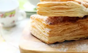 Stos puszystego ciasta francuskiego, idealnego do nauki, jak zrobić ciasto francuskie. Posypane cukrem pudrem.