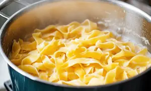 Szeroki, żółty makaron tagliatelle gotuje się w bulgoczącej wodzie. Idealny sposób, jak ugotować makaron do ulubionego sosu.
