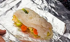 Ryba z piekarnika z warzywami: soczysty filet rybny owinięty w folię aluminiową z marchewką, cukinią i brokułami.