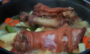 Gotuje się pyszna zupa na golonce wieprzowej z ziemniakami, marchewką i cukinią. Aromatyczny bulion kusi zapachem.