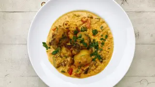 Pyszny ryż z curry z warzywami i kawałkami smażonego kurczaka, udekorowany natką pietruszki.