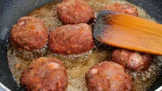 Na patelni smażą się kotlety mielone. Drewniana łopatka pomaga przewracać je, by równomiernie się zarumieniły.