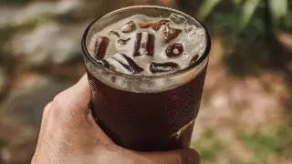 Dłoń trzyma szklankę orzeźwiającego napoju z lodem. To idealny sposób na ochłodę, gdy zastanawiasz się, cold brew co to.