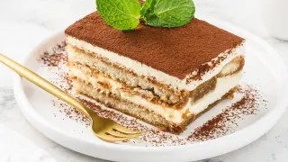 Pyszny kawałek tiramisu z mascarpone, posypany kakao i udekorowany miętą. Idealny sprawdzony przepis na deser.