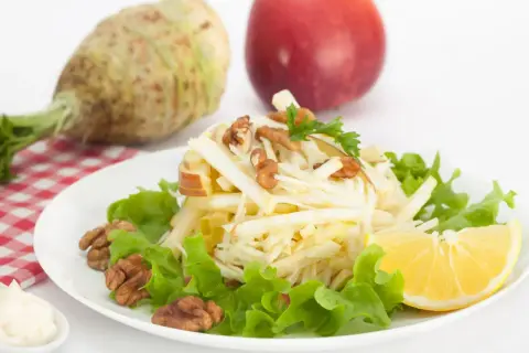 Wykwintna surówka z selera jak w restauracji, z jabłkiem, orzechami i cytryną, na tle selera i jabłka.