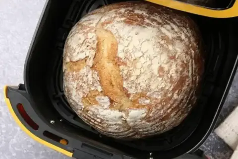 Chleb z airfryer, wypieczony na złoto, z chrupiącą skórką i mąką na wierzchu, gotowy do podania.