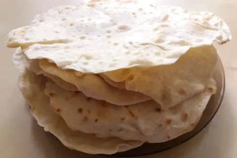 Stos świeżo upieczonych placków tortilla, które wyglądają jak z oryginalnego przepisu. Idealne do wrapów i quesadilli.