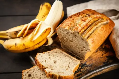 Wilgotne ciasto bananowe, pachnące i pyszne, obok dojrzałych bananów. Idealne na deser lub śniadanie.