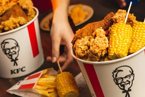 Kukurydza w KFC ma najmniej kalorii. Na zdjęciu kubełki z kurczakiem, frytki i kolby kukurydzy.