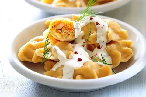 Pyszne pierogi z farszem, polane sosem śmietanowym i posypane koperkiem i pieprzem. Idealne co na piątkowy obiad!