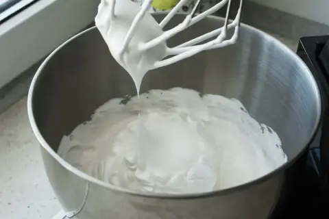 Ubita śmietana z mascarpone, puszysta i idealna do deserów, właśnie powstaje w metalowej misie miksera.