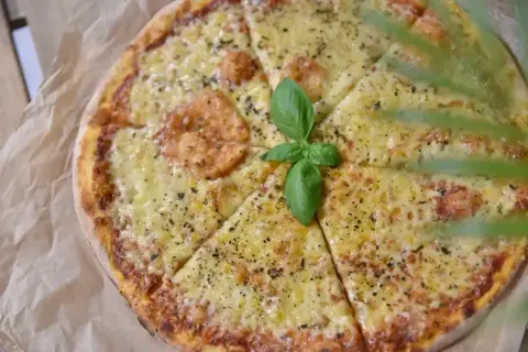 Pyszna pizza z rozpływającym się serem, ozdobiona listkiem bazylii. Idealny ser do pizzy, który zachwyca smakiem.