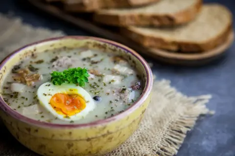 Pyszny żurek z kiełbasą i ziemniakami, ozdobiony jajkiem i natką. Zastanawiasz się, ile kcal ma żurek z kiełbasą i ziemniakami?