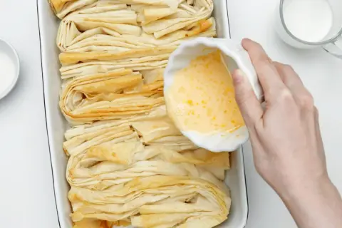 Przygotowanie ciasta filo. W miseczce ubite jajko, obok cukier i mleko. Czas na pyszne przepisy!