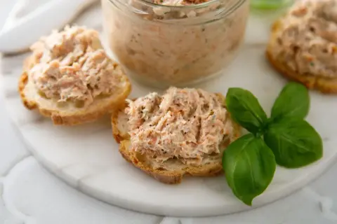 Pyszna pasta rybna na chrupiących grzankach, ozdobiona listkami bazylii. Idealna na szybką przekąskę.