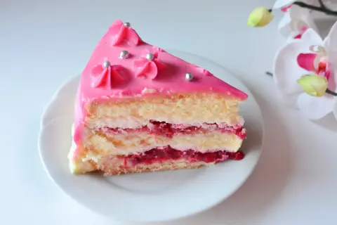 Pyszny kawałek tortu z warstwami biszkoptu, kremu i malinową frużeliną. Wierzch udekorowany różowym lukrem i srebrnymi perełkami. Idealny krem malinowy z mascarpone do tortu.