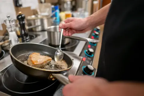 Szef kuchni delikatnie saute kawałek mięsa na patelni, tworząc apetyczną skórkę.
