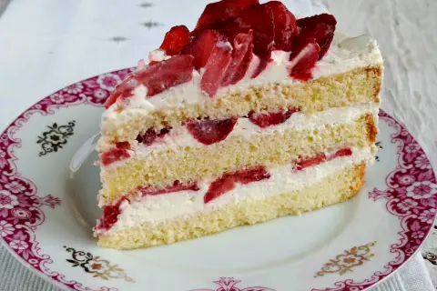Pyszny biszkopt z serkiem mascarpone i bitą śmietaną, przełożony truskawkami. Idealny deser na każdą okazję.