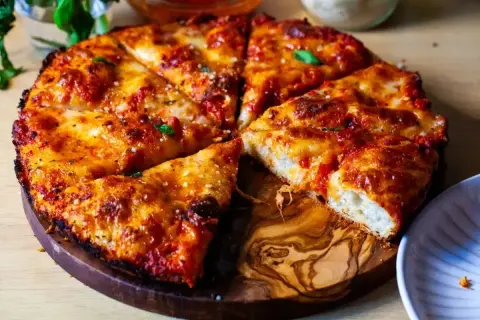 Pyszna pizza rzymska z chrupiącym ciastem, ciągnącym serem i aromatycznym sosem pomidorowym, podana na drewnianej desce.