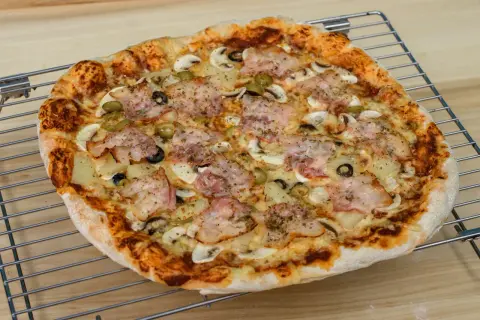 Pyszna pizza z szynką, pieczarkami, oliwkami i ananasem. Idealna na rodzinny obiad, zastanawiasz się ile piec pizze?