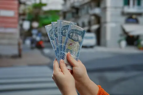 Ręce trzymają pięć banknotów po 1000 forintów. Tyle forintów kosztuje obiad na Węgrzech?