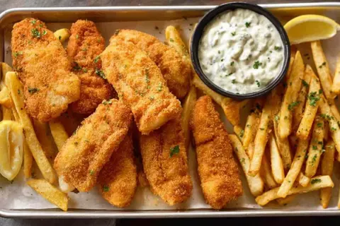 Chrupiące filety rybne i złociste frytki, idealne do domowego fish and chips przepisu. Podane z sosem tatarskim i cytryną.