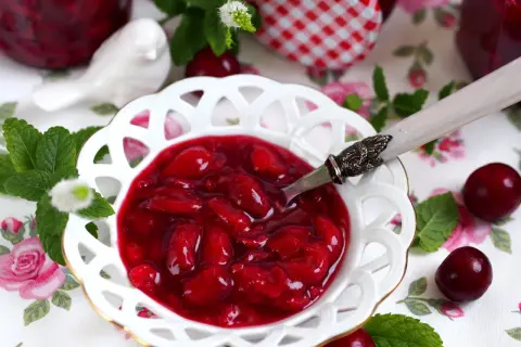 Aksamitna frużelina z wiśni w ozdobnej miseczce, ozdobiona miętą i świeżymi owocami.