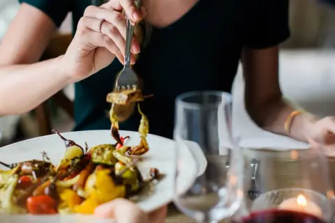 Kobieta je warzywa z grilla, zastanawiając się, ile kcal na obiad.