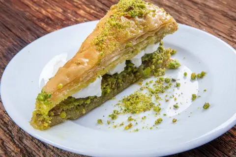 Pyszne ciasto na baklawę z pistacjami i kremem, podane na białym talerzu.