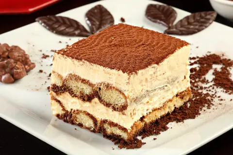 Pyszne tiramisu, idealne na prosty przepis na ciasto cappuccino. Warstwy biszkoptów i kremu, posypane kakao.