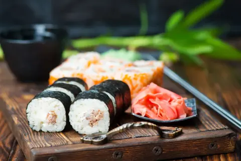 Pyszne sushi z kremowym nadzieniem, obok marynowany imbir i miseczka na sos do sushi.