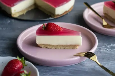 Pyszny deser z mascarpone i galaretką, udekorowany truskawką, czeka na talerzyku.