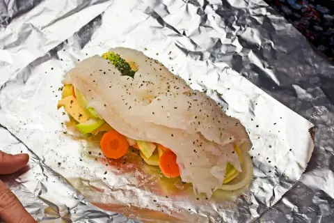 Ryba z piekarnika z warzywami: soczysty filet rybny owinięty w folię aluminiową z marchewką, cukinią i brokułami.